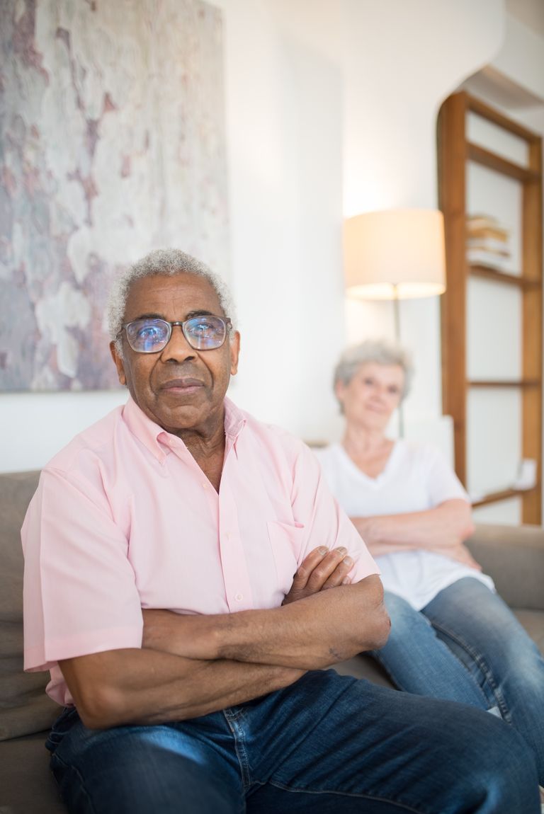 Senior adults relaxing with arms crossed on a couch.